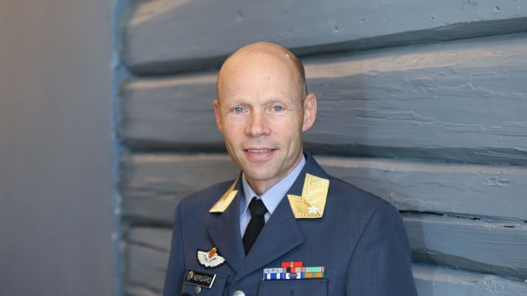Portrettbilde av mann i uniform som smiler mot kamera