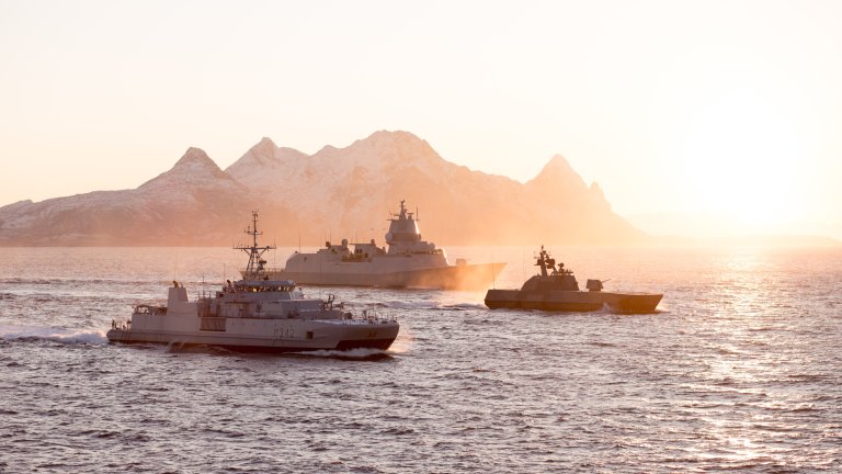 Tre maritime fartøy i solnedgang