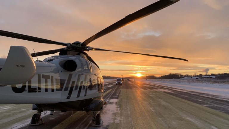 Politihelikopter på rullebane i lav sol og med snø på bakken