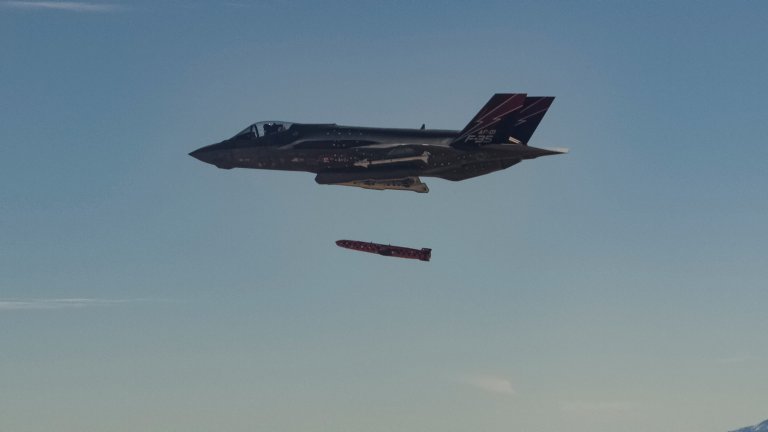 Et F-35 kampfly i flukt slipper et testmissil under i dagslys mot en klar blå himmel.