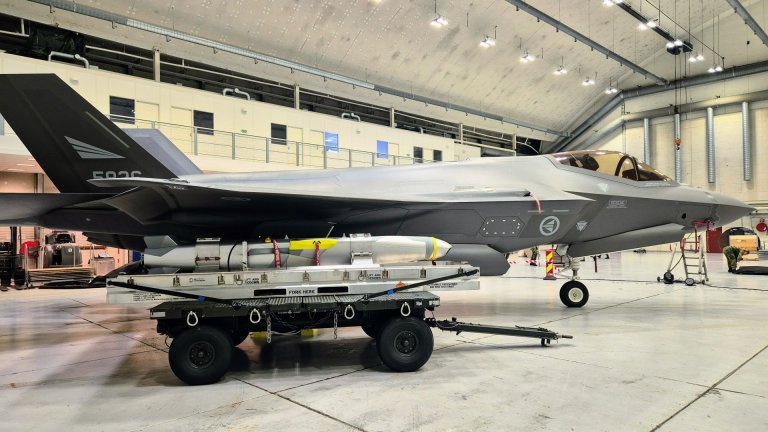 F-35 kampfly i en hangar med en vogn lastet med et missil plassert ved siden av