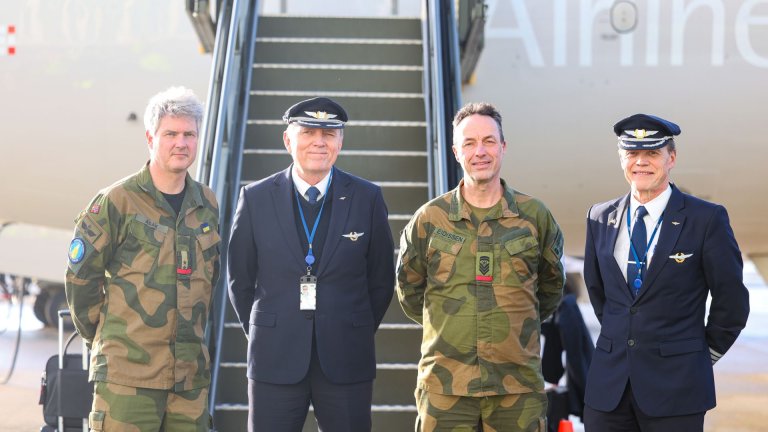 To personer i militæruniform og to personer i flyveruniform foran en flytrapp