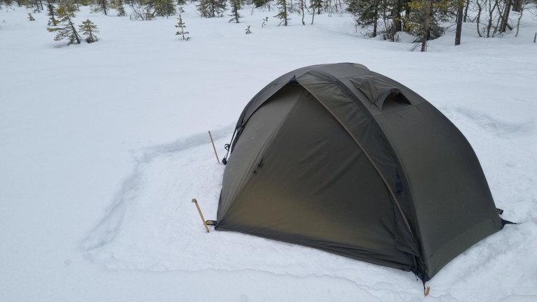 Telt står i snøen i skog