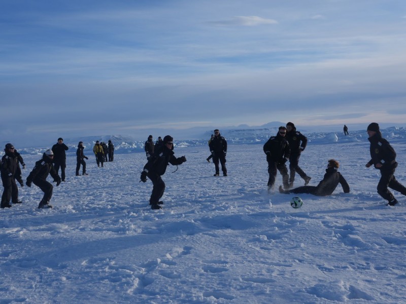 KV Svalbard har ankret opp ved en egnet havis hvor de menige kan gå ned fra båten, og spille fotball. En isbjørnvakt i sees i horisonten, og er alltid med når personell skal ut på isen. 