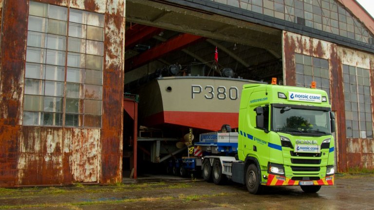 KNM Skrei, en motortorpedobåt, fraktes med bil inn i en hangar.