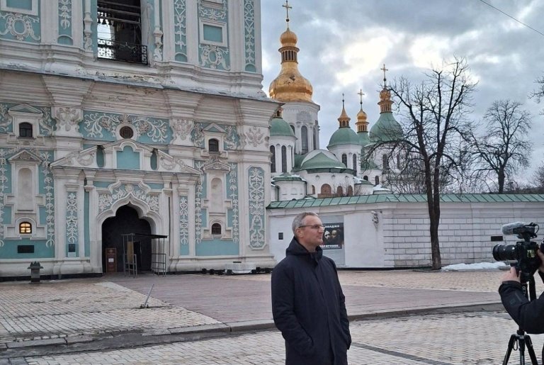 Mann blir filmet foran staselig bygg med gullkupler