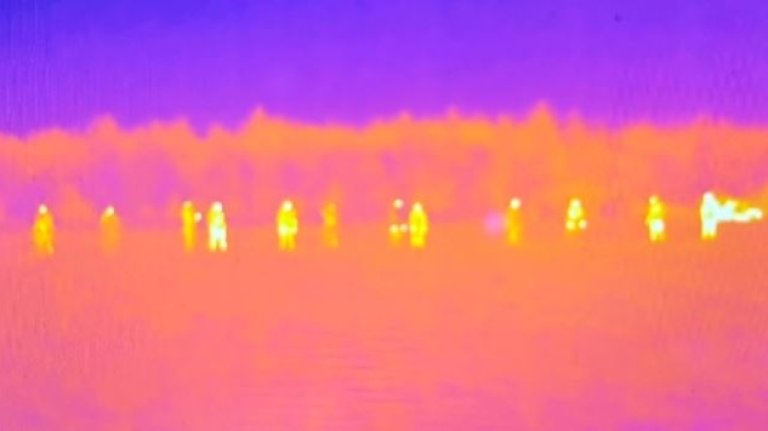 Termisk bilde som viser flere personer som varme silhuetter i terrenget